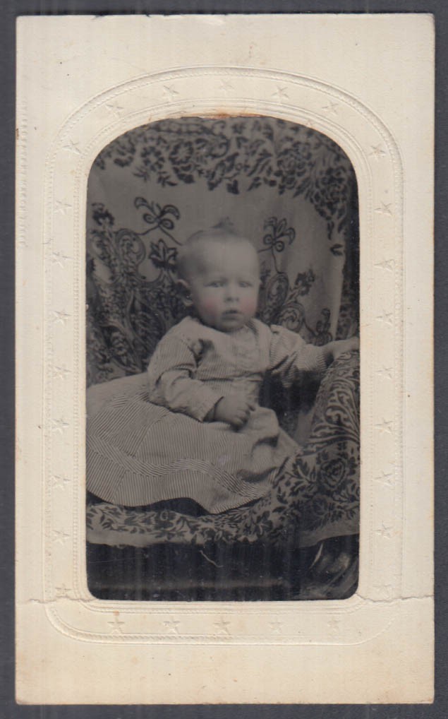 Pink-cheeked baby in fancy studio chair tintype in paper matte 1860s